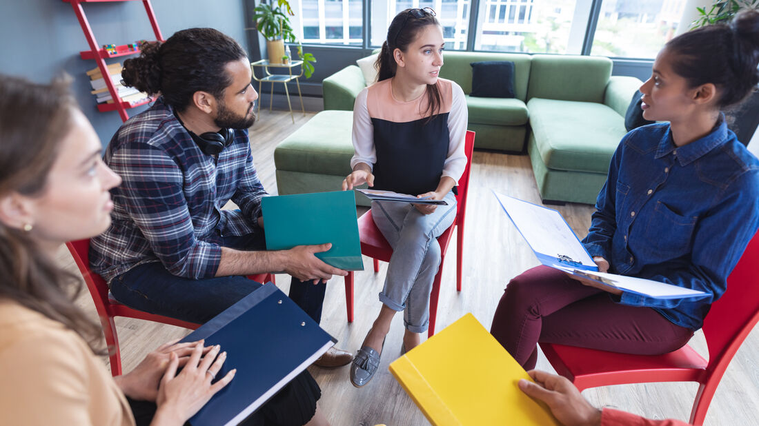 A clinical team gathered around a table in a sunlit meeting space