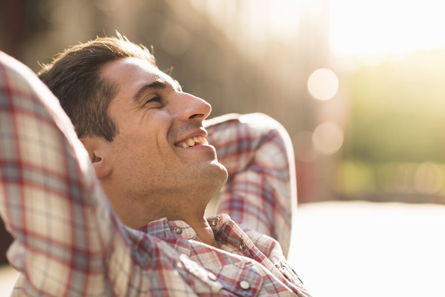 A man reclining outdoors in soft daylight, eyes half-closed, calm