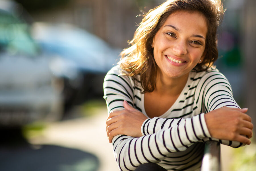 A young mother smiling softly outside, soft natural light